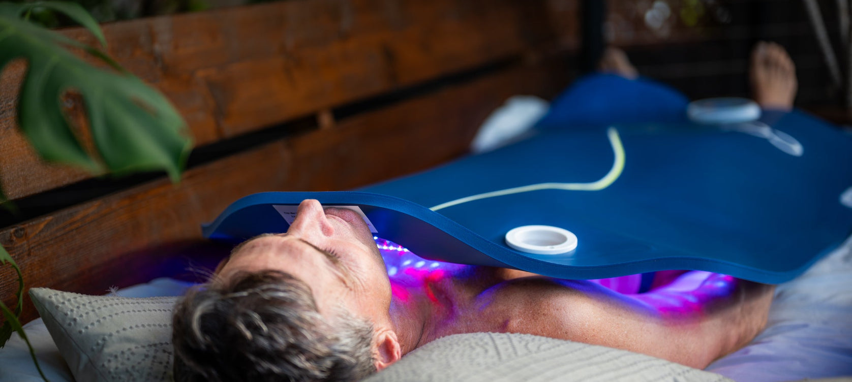 A man using a Celluma XL in his bed for a full-body LED light therapy treatment