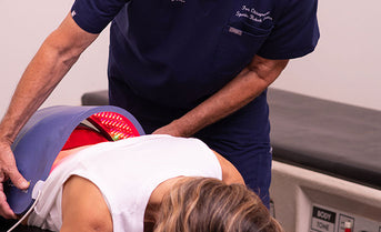 Doctor applying a Celluma light therapy device on a patient's back in a clinical setting