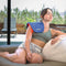 Women sitting on the couch using the Celluma device on aches and pains mode for a shoulder treatment.