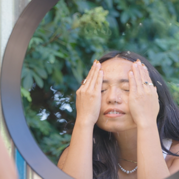 Woman looking in the mirror after washing her face and beginning her wellness routine