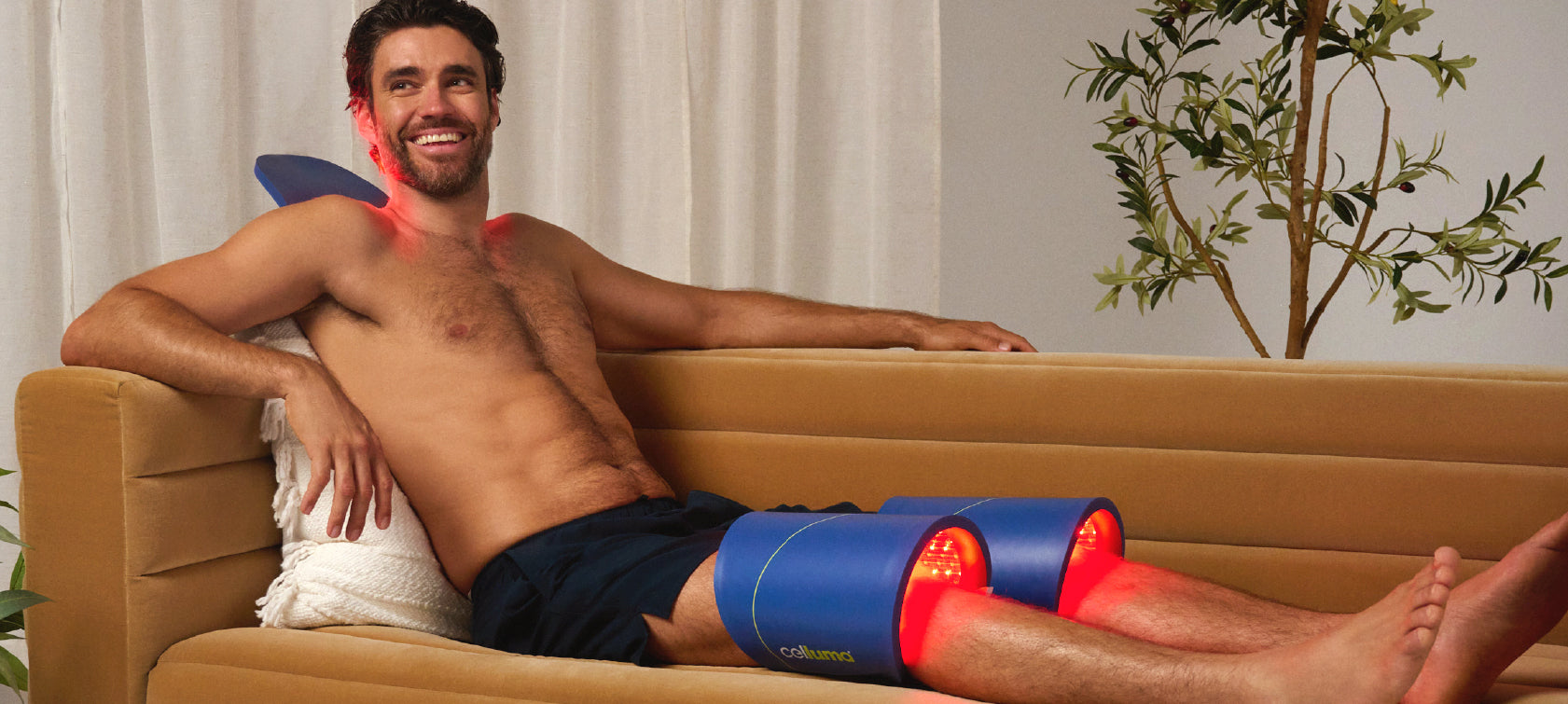 Man lying on a couch with a large Celluma panel wrapped around each knee.