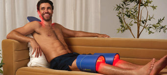 Man lying on a couch with a large Celluma panel wrapped around each knee.