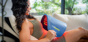 Woman sitting up on a couch placing the Celluma large panel over her stomach in body contouring mode.