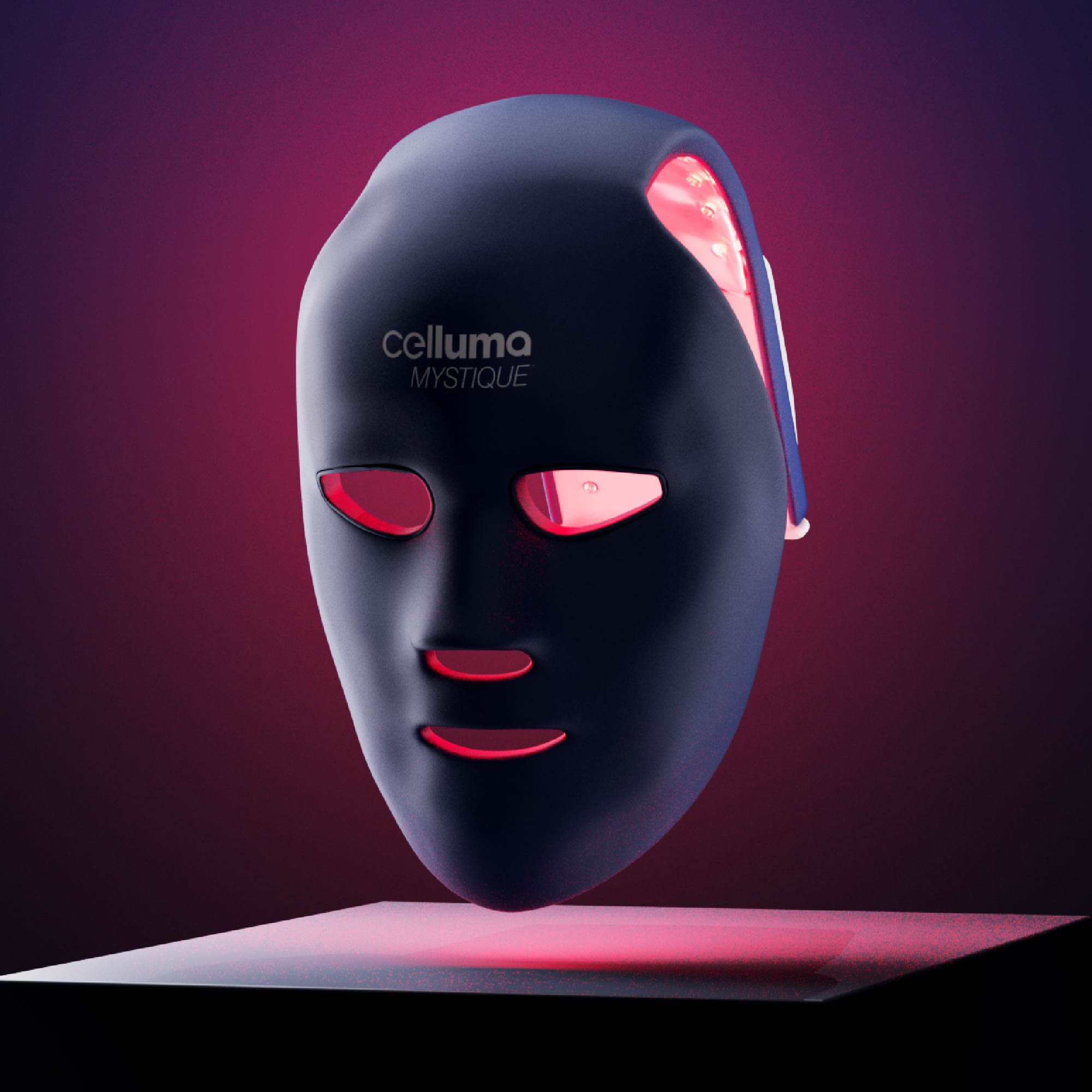 Celluma MYSTIQUE mask turned on and tilted slightly forward and floating above a flat surface.
