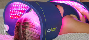 Woman lying down on a bed with a large Celluma panel in the C-shape over her face and another large panel over her stomach.