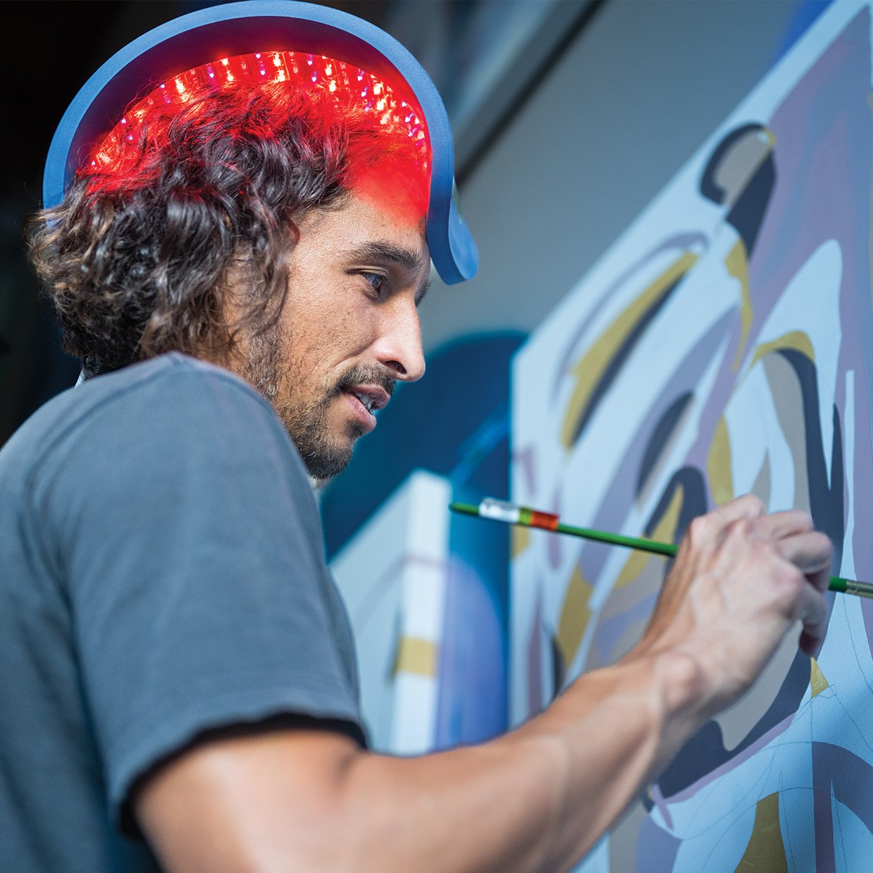 A man painting while using the Celluma RESTORE to stimulate hair growth at home