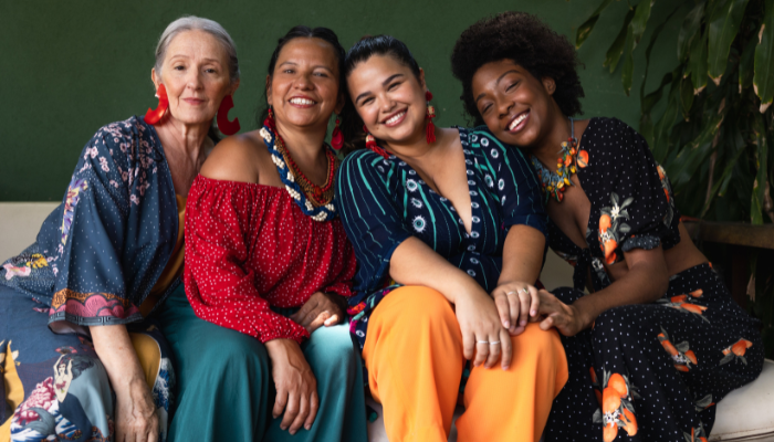 Group of diverse women with alopecia smiling and sitting together on a couch