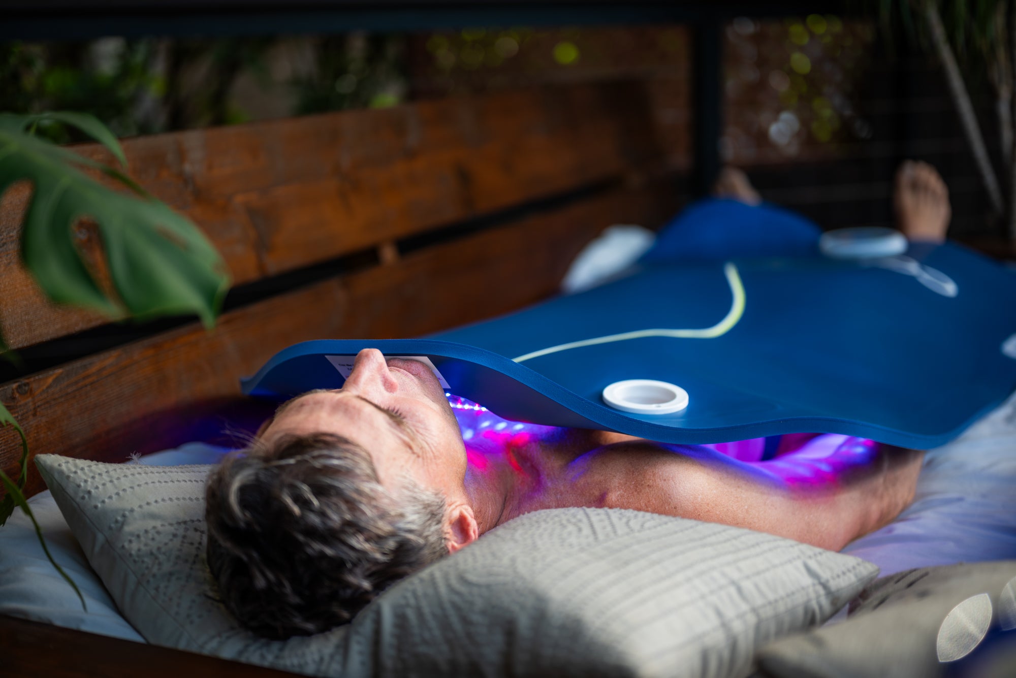 A man using a Celluma XL in his bed for a full-body LED light therapy treatment
