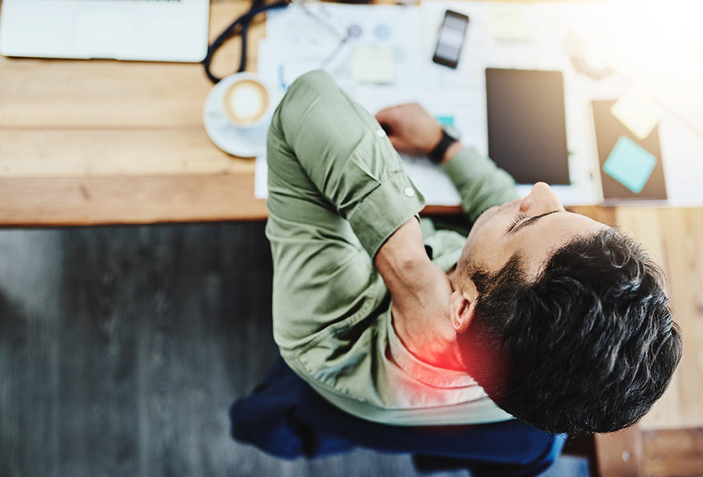 A man at his office desk dealing with chronic pain