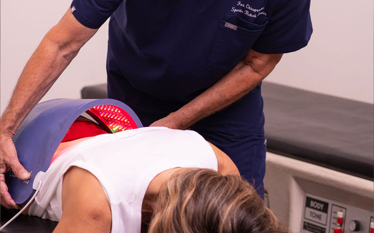 Doctor applying a Celluma light therapy device on a patient's back in a clinical setting