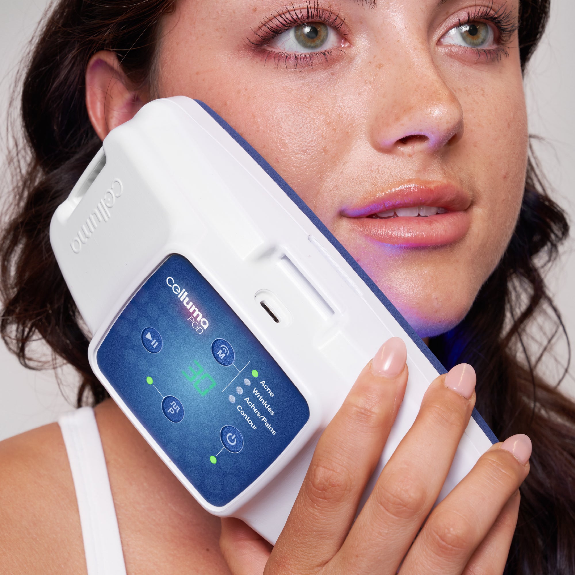 Woman using Celluma POD Series 2 LED red light therapy device against her face for acne and wrinkle treatment.