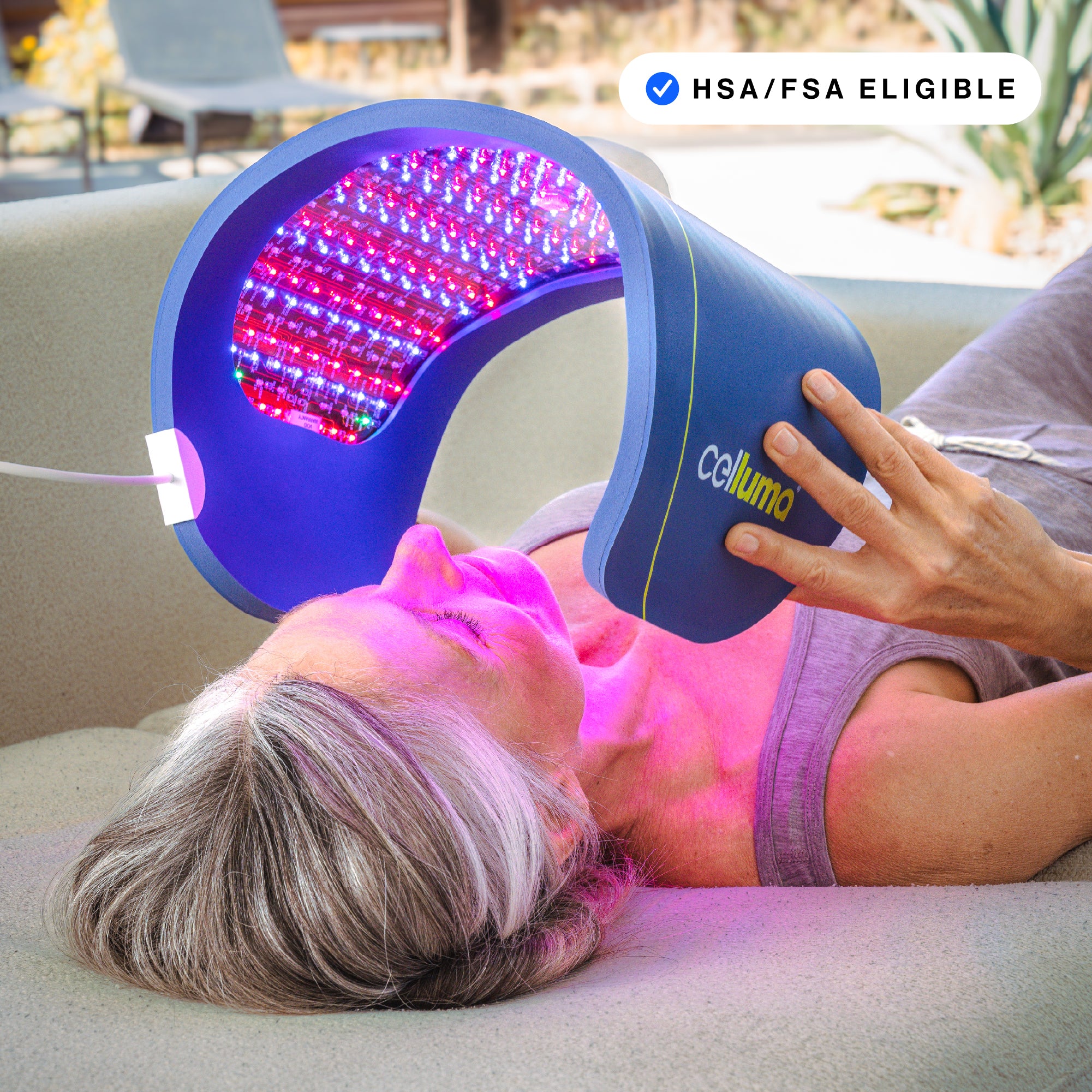 Older woman using Celluma PRO LED light therapy panel on face for anti-aging and wrinkle reduction. HSA/FSA eligible medical-grade red light device.