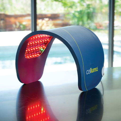 Close Up of a large, single-panel Celluma LED red light therapy device emitting light while sitting on a reflective countertop.