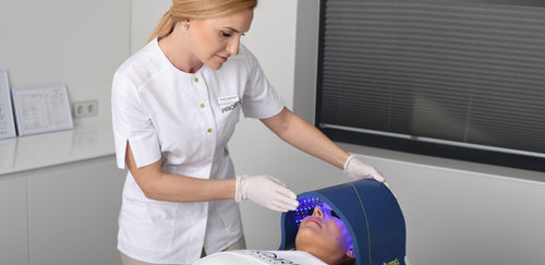 Aesthetician using a Celluma light therapy device on a client's face during a skincare treatment.