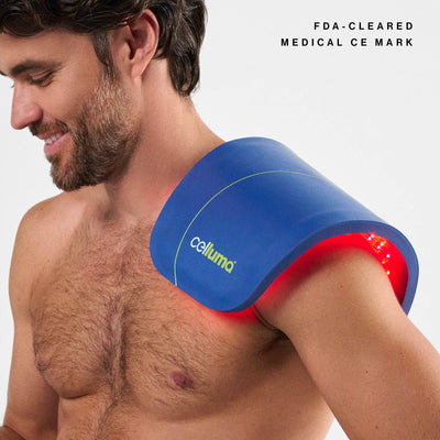 Man using a blue and red Celluma device on his shoulder with a gray background