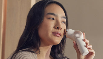 Woman using a small LED device on her face