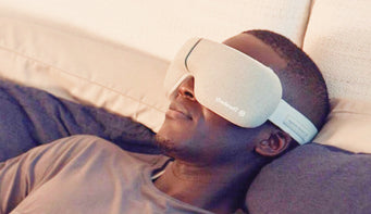 Man wearing a therapeutic eye mask while lying on a bed.